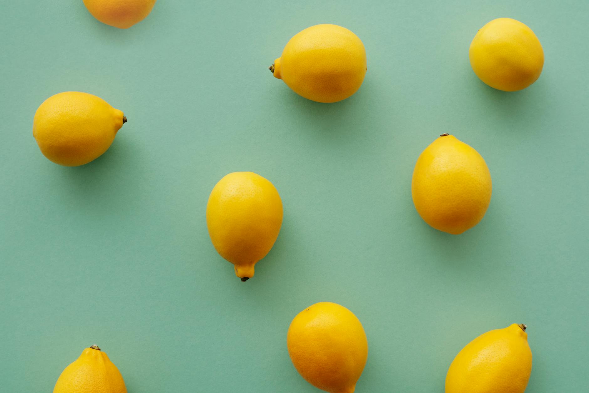 Bright yellow lemons on a pastel green background, symbolizing freshness and the natural cycles of pleasure