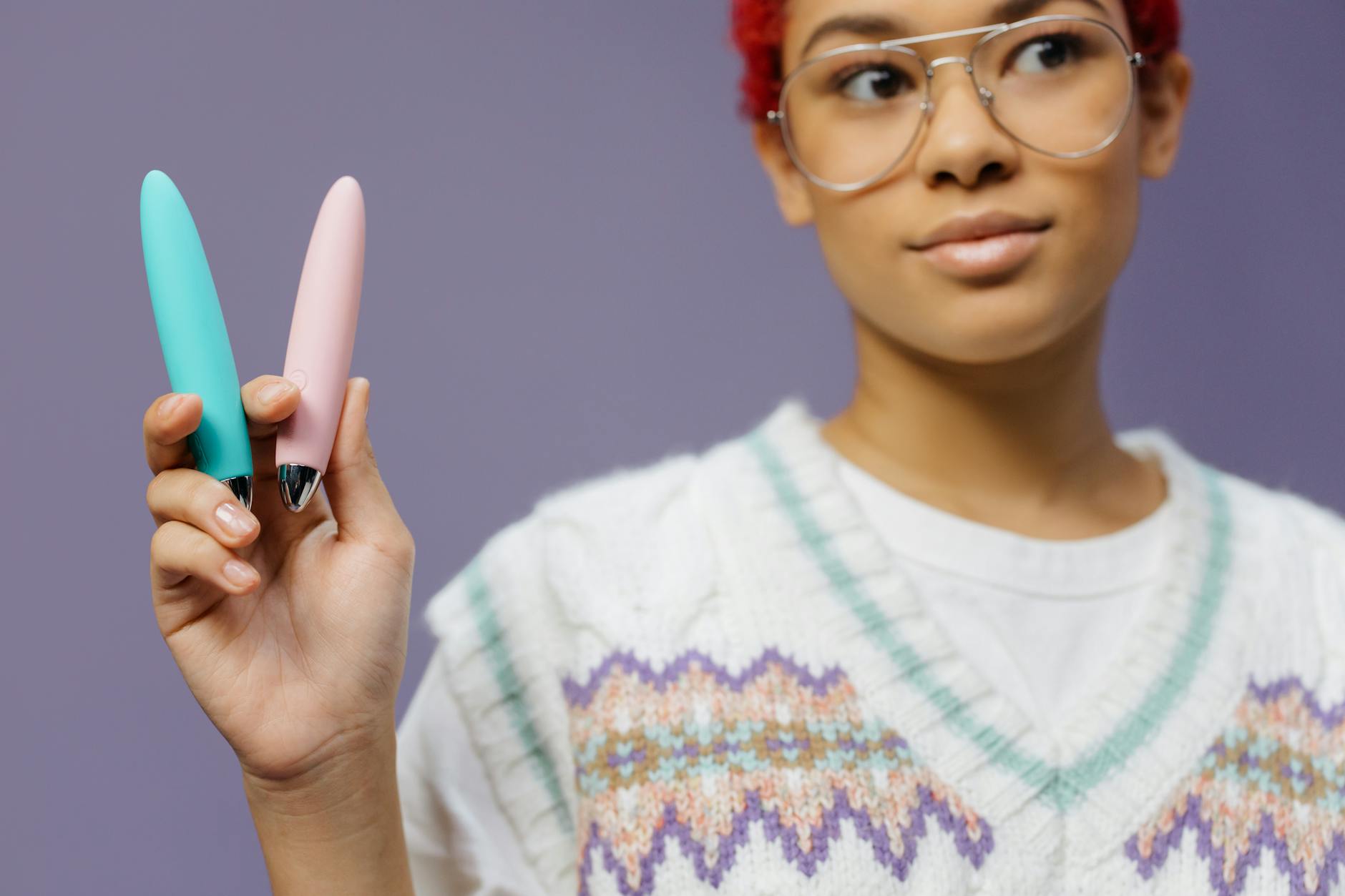 Woman holding colorful vibrators against a purple background, representing rediscovering pleasure with lemon vibrators