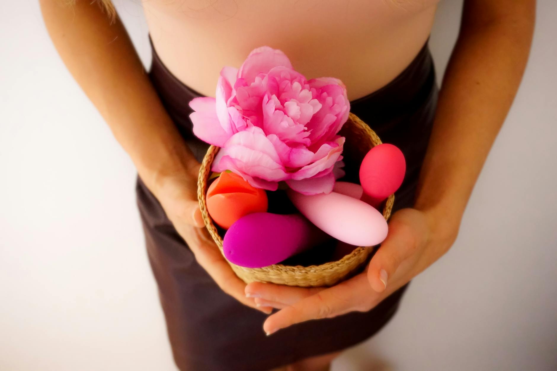 A young couple standing together indoors, holding a vibrator and smiling comfortably
